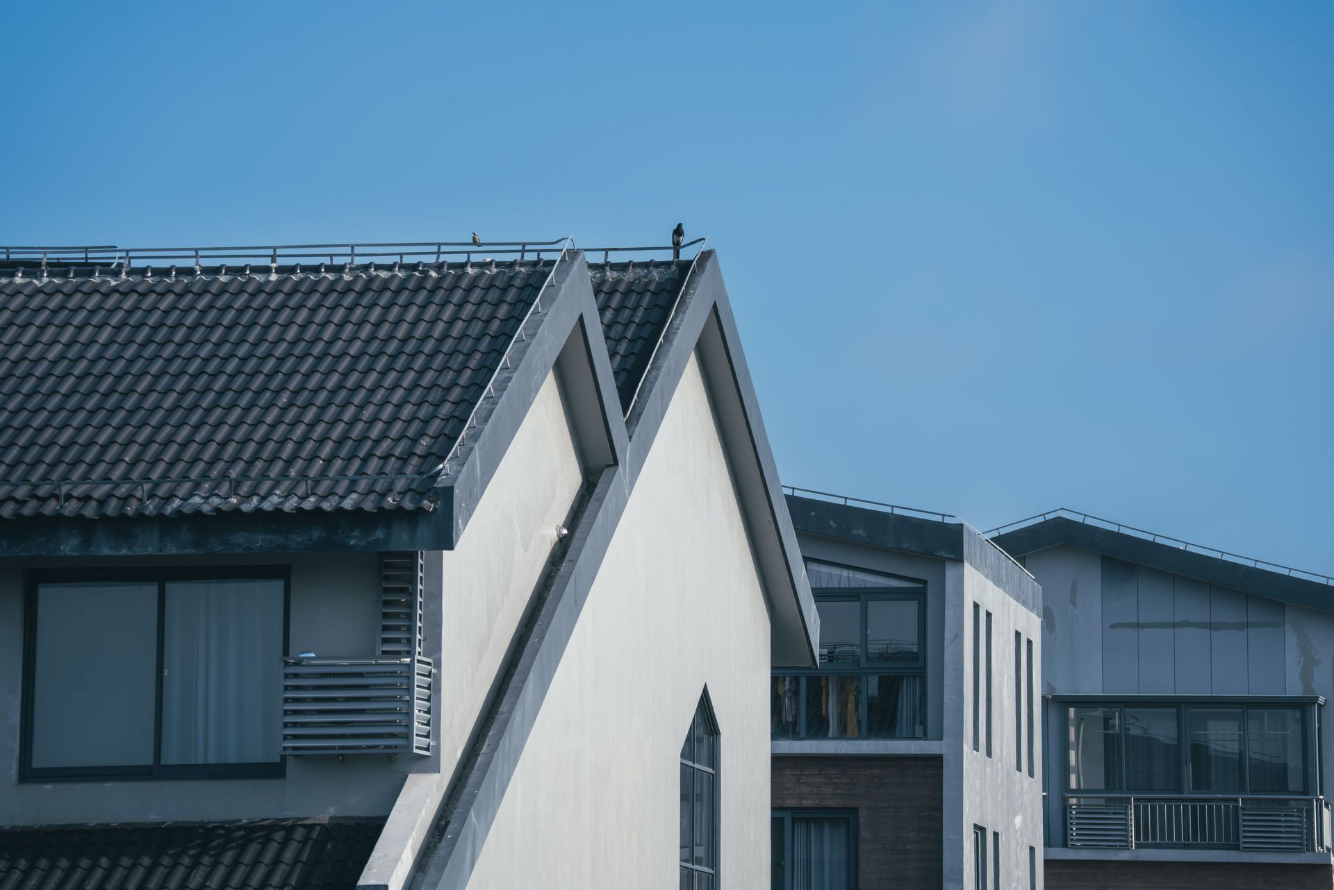 Modern residential buildings with unique architectural rooftops under a clear blue sky.
