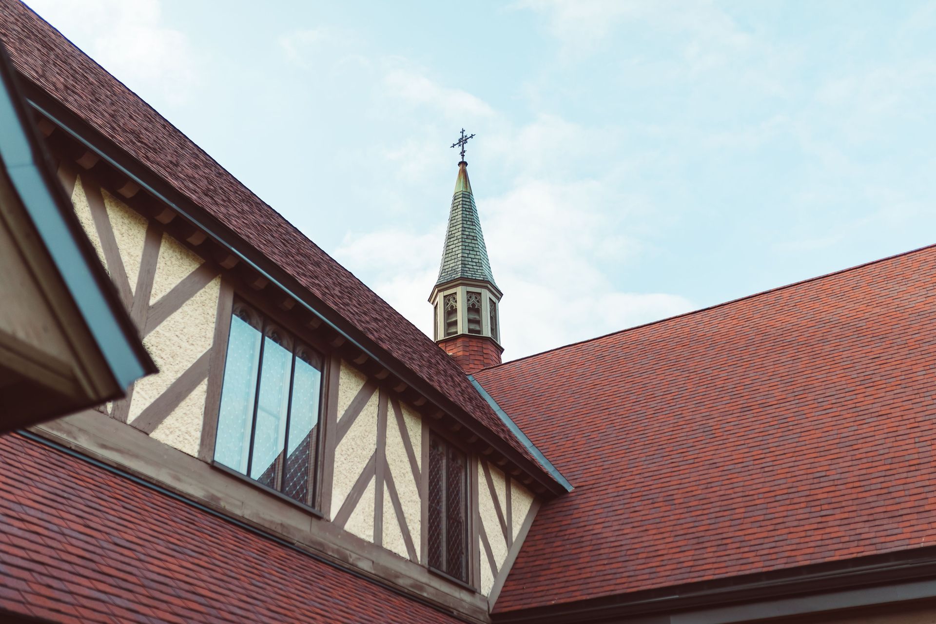 Close-up view of a church steeple with timbered architecture against a clear sky.